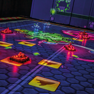 7 joueurs dans leur kart sur le jeu BattleVirus, vue d'ensemble avec gros virus au centre et cases bonus surle fond mauve